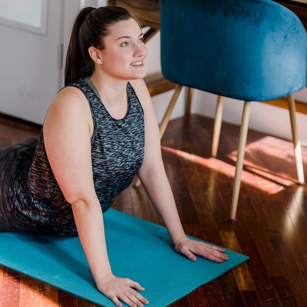 A person with a smile starting a simple yoga stretch in a bright room.
