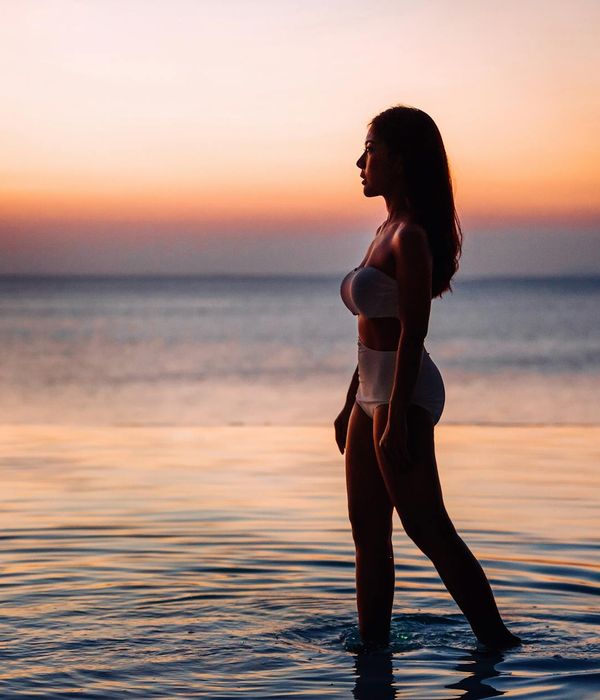Woman in a peaceful yoga pose against a sunrise background.